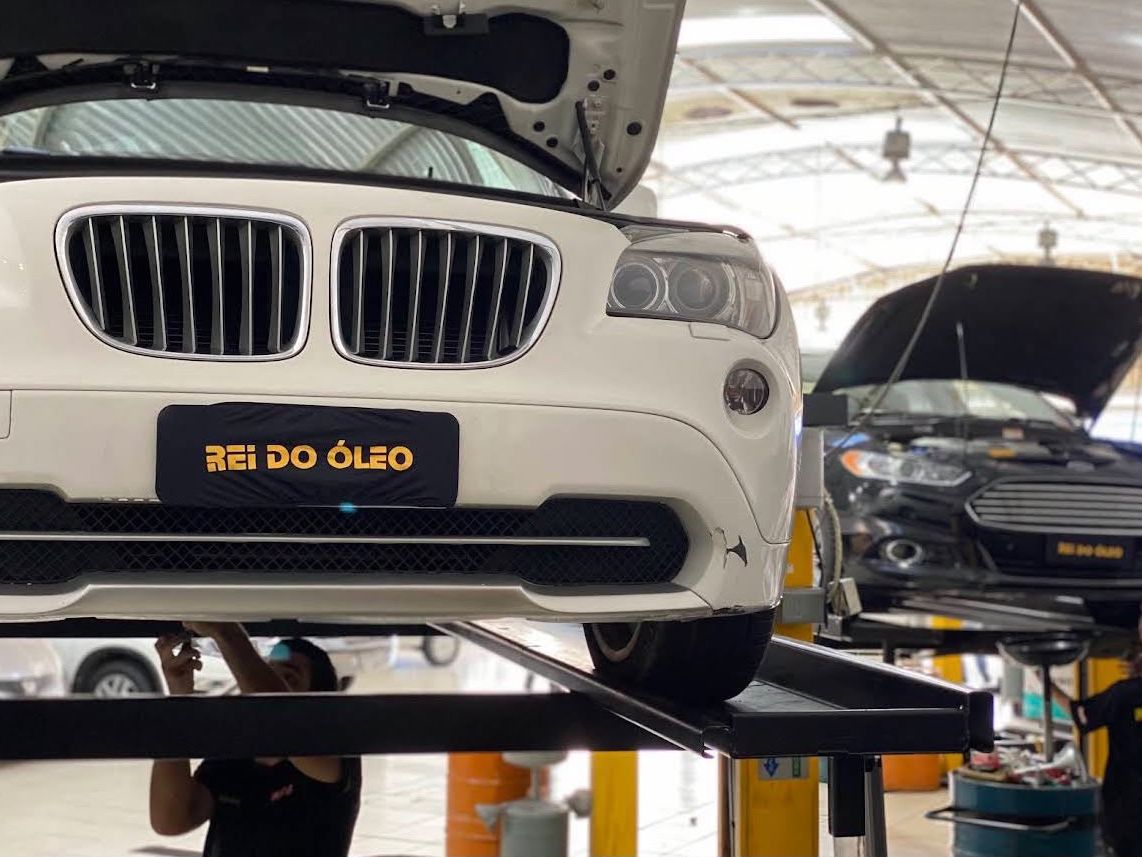 BMW no elevador com a placa Rei do Óleo ao fundo
