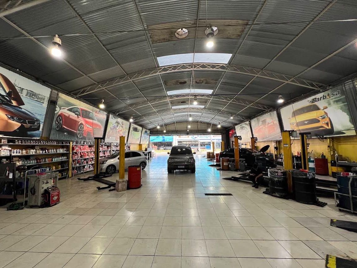 Interior da oficina com elevadores em linha e veículos em atendimento