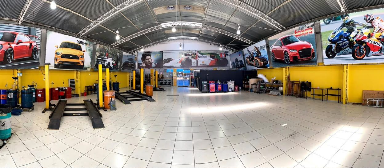Vista panorâmica da oficina com painéis de carros e motos